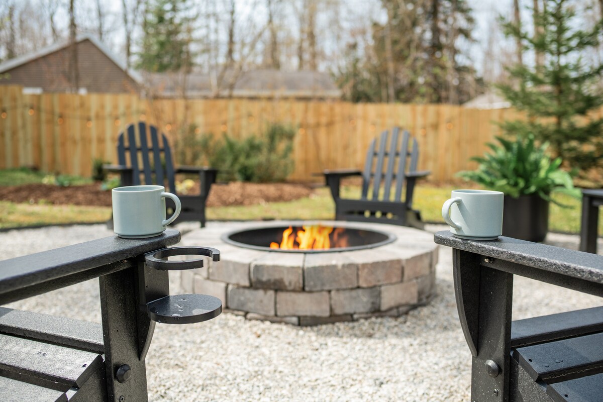 Stone fire pit with Adirondack chairs in the wooded backyard